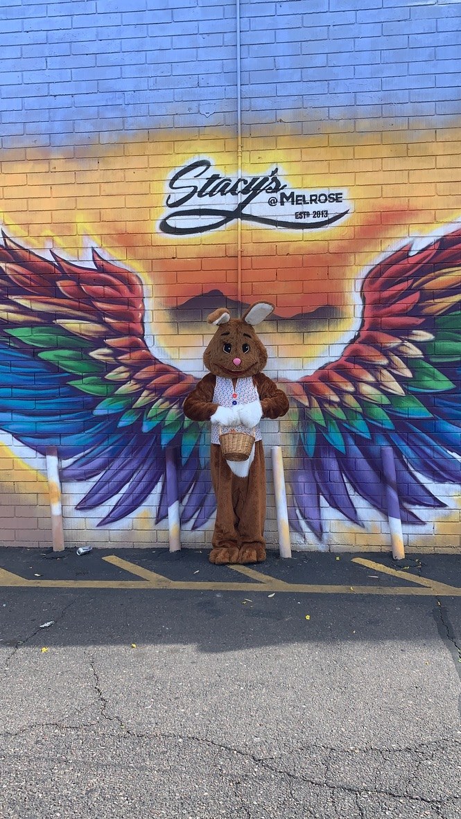 Easter Bunny standing in front of colorful wings mural